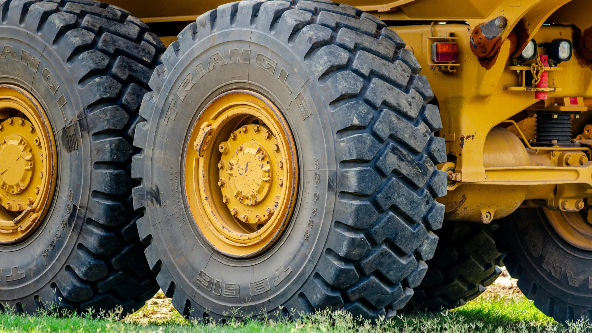 Massive, rugged rubber tires on a yellow heavy industrial dump truck or earthmover, designed with reinforced compounds for high durability in mining and construction.