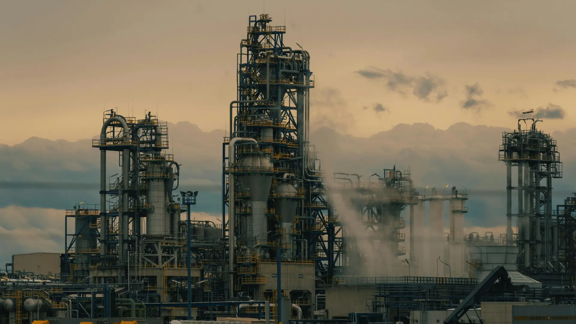 Exterior view of a heavy industrial chemical processing plant and refinery showing industrial infrastructure and exhaust stacks.