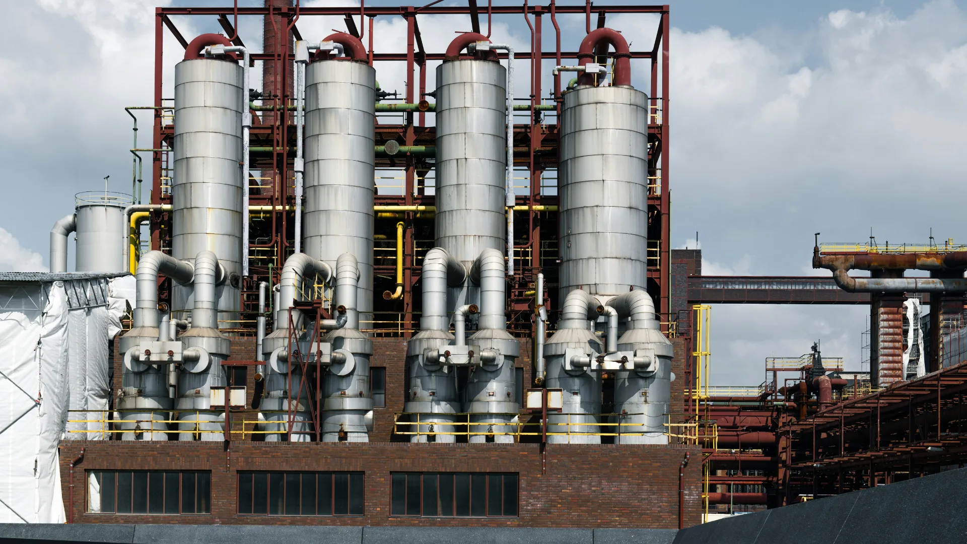 Large vertical steel silos and complex piping infrastructure at a heavy industrial chemical processing and manufacturing plant.