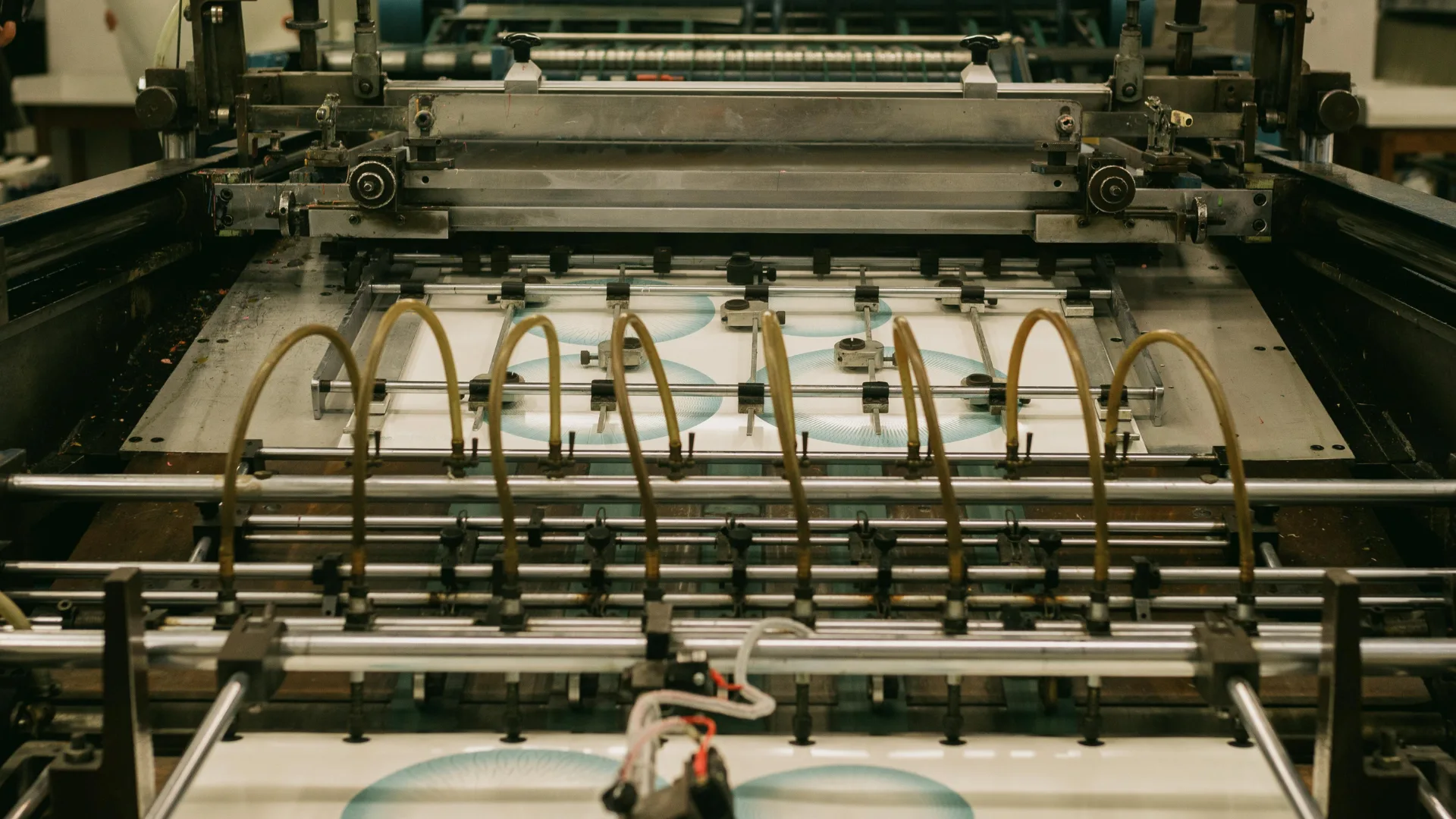 High-speed industrial offset printing press machinery feeding sheets of paper, utilizing specialized ink pigments for commercial print production.