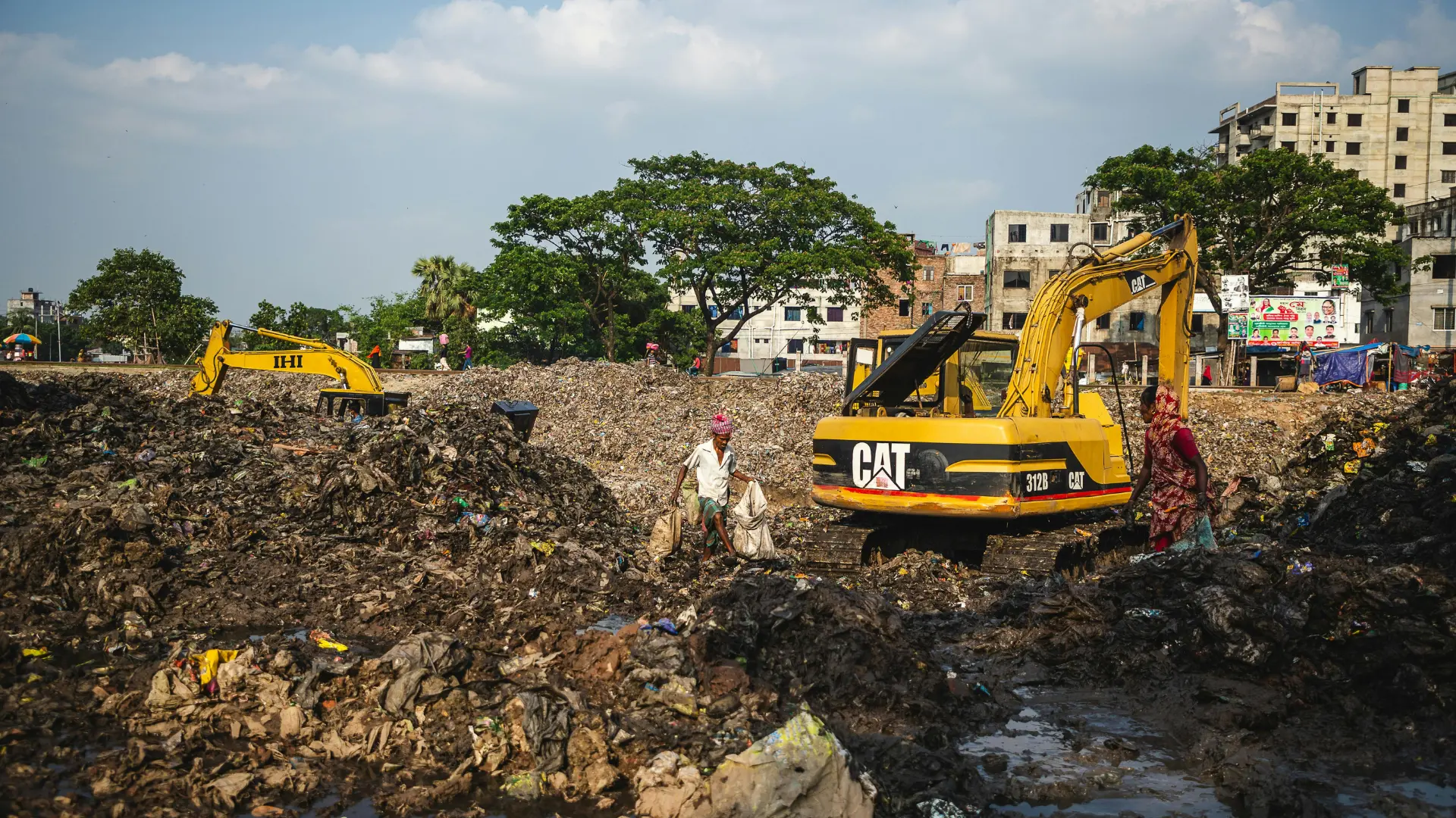Excavators working at a large municipal solid waste landfill site requiring environmental odor control and leachate treatment.