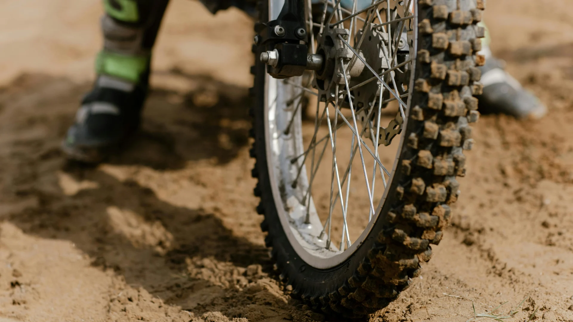 Close-up of a rugged off-road motorcycle tire resting on dirt, highlighting the extreme high-wear resistance and tread durability provided by specialized carbon black rubber compounds.