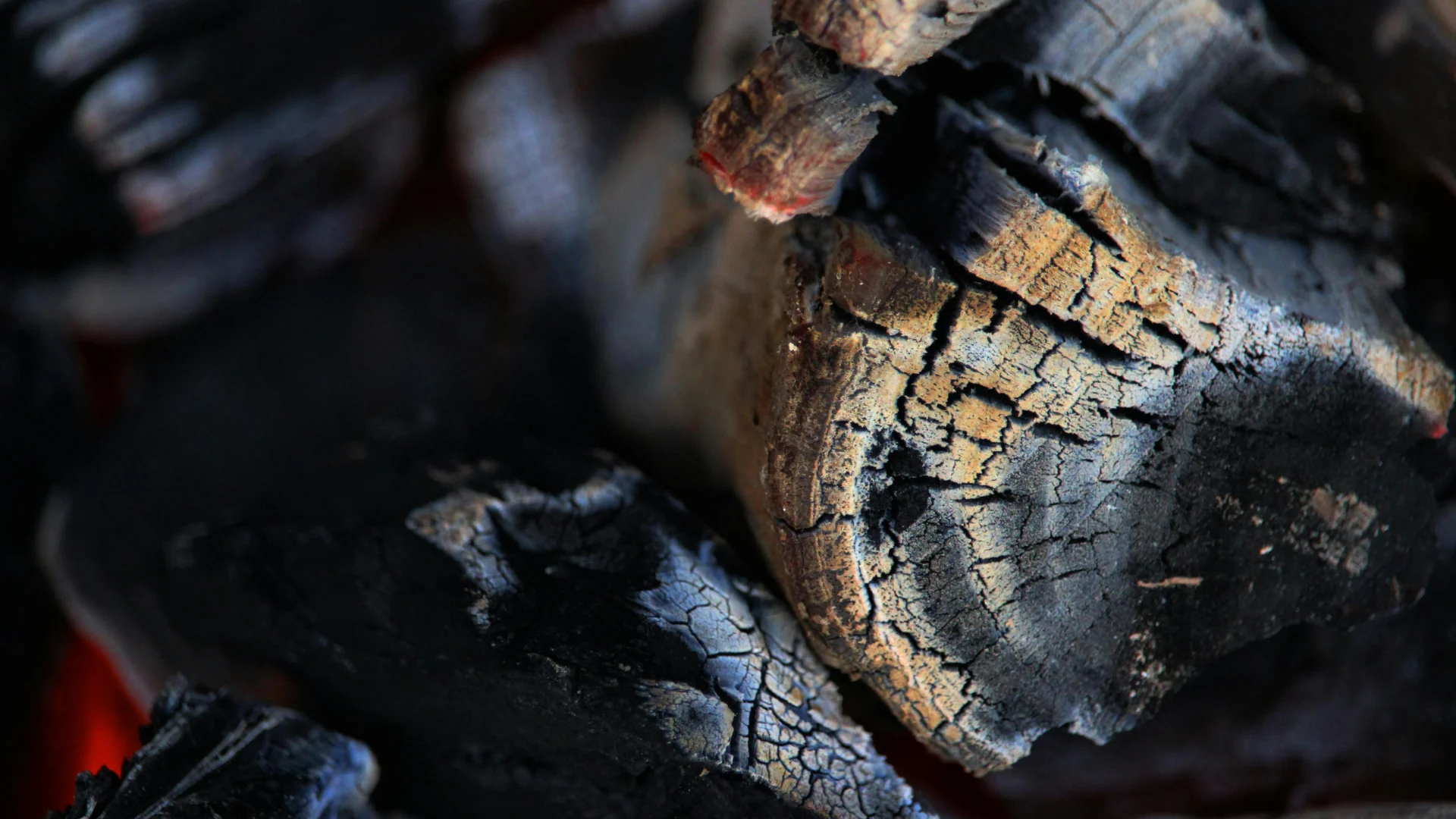 Macro shot of premium natural lump charcoal smoldering with glowing red embers and cracked textures, highlighting high-quality carbon products.