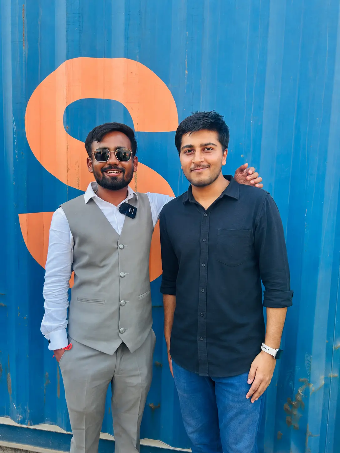 The founder of Zenon Exports, a premium industrial carbon supplier, standing with a colleague in front of a blue shipping container.